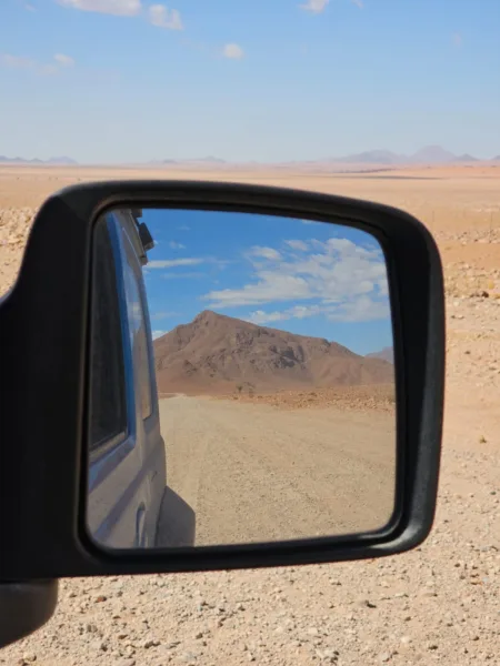 Reflejo en el espejo del coche 4x4 en una carretera solitaria de Namibia